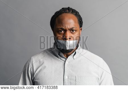 Studio Shot Of Sad African American Voiceless Speechless Guy Looking At Camera, Mouth Closed With Ad