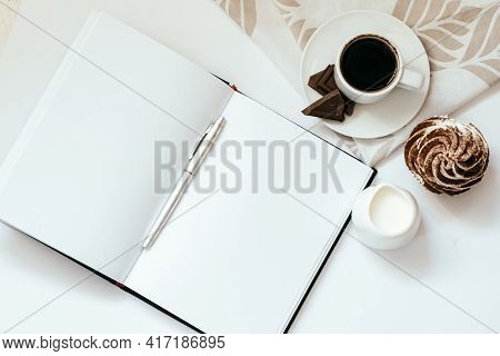 A Cup Of Coffee With Chocolate And Cupcakes And Open Notepad