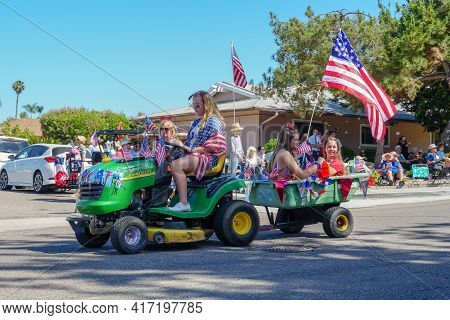 Young Girls With American Flag Riding Small Lawn Mower And Parading At The 4th Of July Independence 