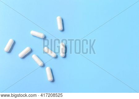 White Pill Capsules On A Blue Background. Isolate. Close-up. Medical Concept. High Quality Photo