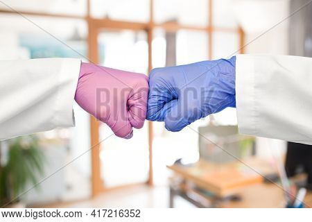 medicine, health protection and healthcare concept - hands of doctors in gloves make fist bump gesture over office background