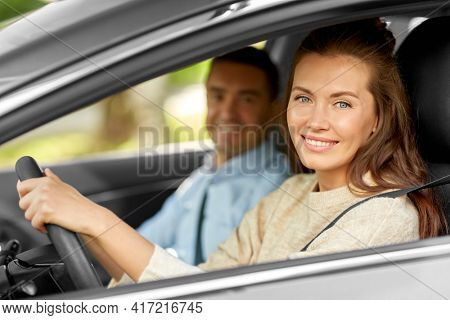 driver courses and people concept - car driving school instructor teaching young woman to drive