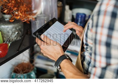 Cropped View From Shoulder Of Caucasian Seller In Checkered Shirt And Apron Using Digital Tablet For