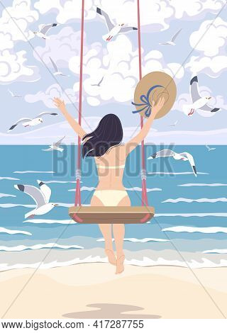 Young Woman With Long Dark Hair Swinging On A Swing At The Sea Coast. Dreamy Girl Holding Straw Hat,