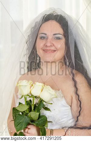 A Joyful Jewish Bride With Her Face Covered With A Veil With A Bouquet Of White Roses Before Perform