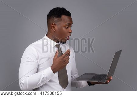 Young Black Businessman Using Laptop And Taking Notes At Worklace In Modern Office, Free Spac