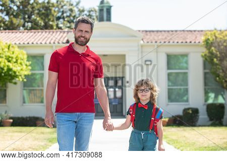 American Father And Son Walking Trough School Park.