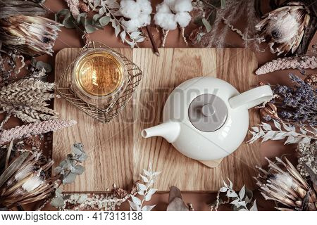 Composition With Dry Wildflowers And Natural Herbal Tea In A Teapot On A Wooden Surface.