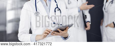 Unknown Woman Doctor Iusing Tablet Computer In Her Hands, While Standing In Clinic. Medicine Concept