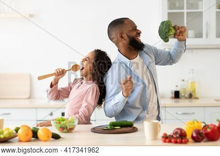 Black Father And Daughter Singing In The Kitchen Having Fun