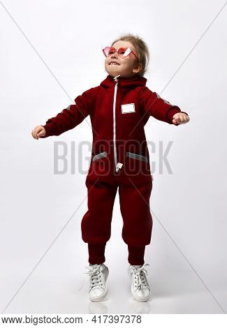 Cute Little Doshkolnitsa Warm Sportswear With A Hood And White Sneakers Jumping With Arms Raised Abo