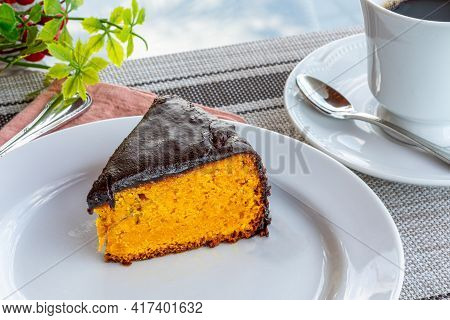 Carrot Cake With Chocolate Icing, Accompanied By A Cup Of Coffee