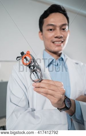 A Male Doctor Poses Holding An Eyeglass Gauge Frame