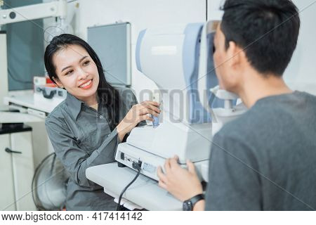 A Female Doctor And A Male Patient Doing An Eye Check Using A Device