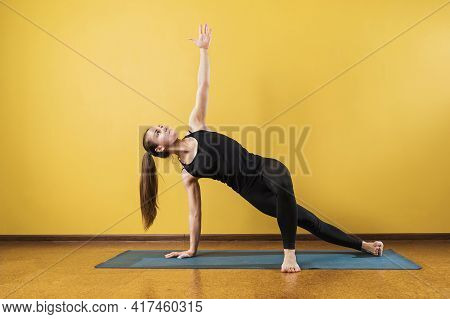Woman Practicing Yoga, Doing Vasishthasana Exercise, Side Plank Pose, Exercising On A Mat In The Stu