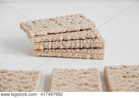 Stacked Rye Crisp Bread On A White Wooden Background. Copy, Empty Space For Text