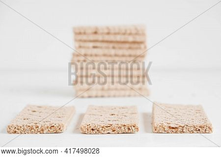 Stacked Rye Crisp Bread On A White Wooden Background. Copy, Empty Space For Text