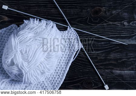 A Skein Of White Yarn With Z Knitting Needles And A Blank For Needlework On A Dark Wooden Background
