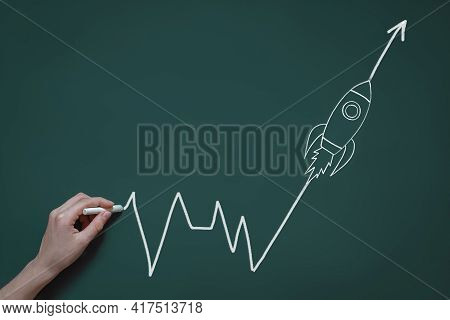 Hand Draws In Chalk On A Blackboard A Graph With A Flying Rocket, The Concept Of Success, A New Idea