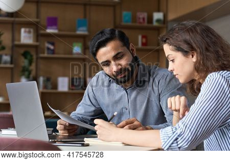 Two Multiethnic Professionals Colleagues Working Together With Laptop And Papers In Office. Indian M