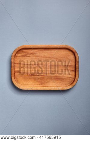 Empty wooden tray on textured dark blue table. Rectangular wooden dish top view. Kitchen minimal flat lay
