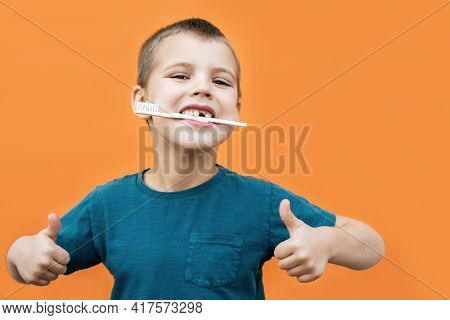 Boy Without Milk Upper Tooth In Blue T-shirt Holds Toothbrush In His Mouth On The Orange Background.