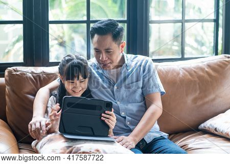 Asian Family Girl Kid And Father Using Tablet Playing Internet Online Together In Living Room At Hom