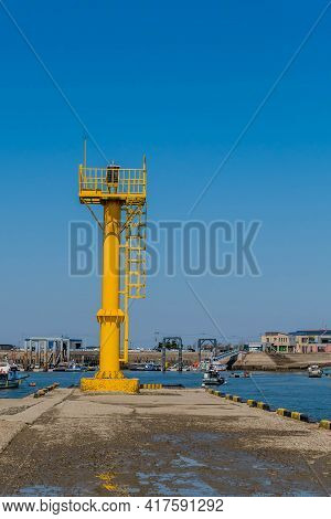 Pyeontaek, South Korea; April 14, 2021: Yellow Lighthouse On Concrete Pier Overlooking Jeongok Port.