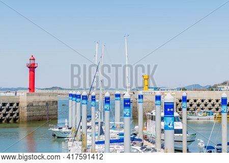 Red Lighthouse On Pier Overlooking Yachts.