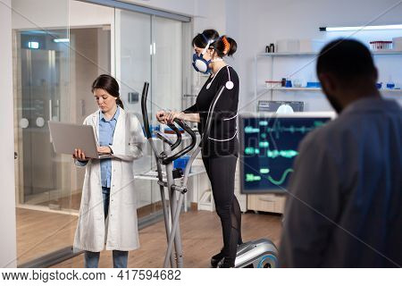 Team Of Professional Doctors Measuring Health Conditions Of Woman Athlete