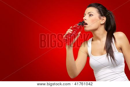 Giovane ragazza avendo bevanda isotonica isolato su sfondo rosso