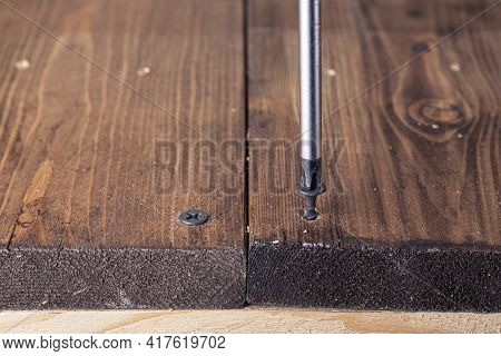 A Screwdriver And Screw On A Wooden Background. Screwdriver Of Chromium Vanadium Steel. Construction