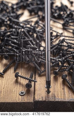 A Screwdriver And Screw On A Wooden Background. Screwdriver Of Chromium Vanadium Steel. Construction
