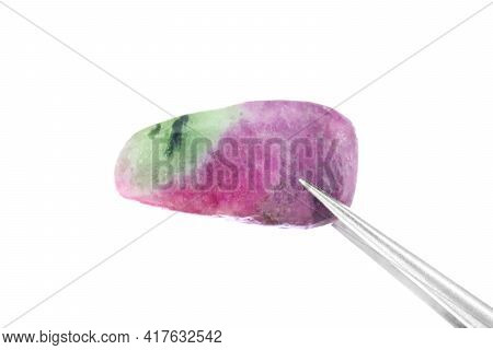 Ruby Zoisite Jewel Stone Texture In Tweezers On Light Surface Background. Macro Closeup.