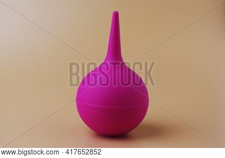 Douche Bag Fuchsia Color On Beige Bacdrop. Medical Tool
