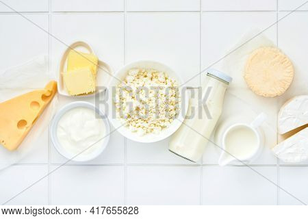 Glass Of Milk, Cottage Cheese, Ricotta, Sour Cream, Cheese, Camembert And Butter On White Table Back