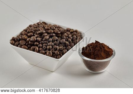 Roasted Whole Peaberry Coffee Beans And Freshly Ground Coffee Powder On A White Background