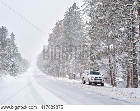Fort Collins, CO, USA - April 19, 2021: Toyota 4RUnner SUV (2016 Trail model) in a heavy springtime snowstorm in the Poudre River Canyon  in Colorado Rocky Mountains, winter travel concept.