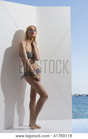 blonde MÃ¤dchen im Bikini in der NÃ¤he der Wand mit Hand in der NÃ¤he der Hals
