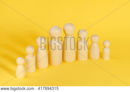Family Of Eight 8 Members Made From Wooden Figurines On Yellow Background. Family With Many Children