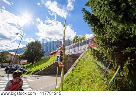 Chamonix, France - Aug 13, 2017: Woman Walking Crossing Street In Central Chamonix With Train Drivin