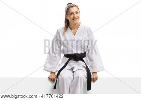 Woman in karate kimono and black belt sitting on a banner isolated on white background