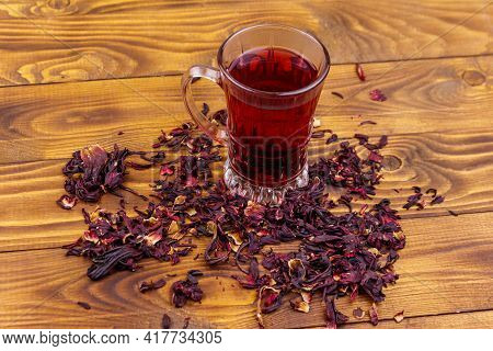 Glass Cup Of Red Hibiscus Tea (carcade, Roselle) On Wooden Table