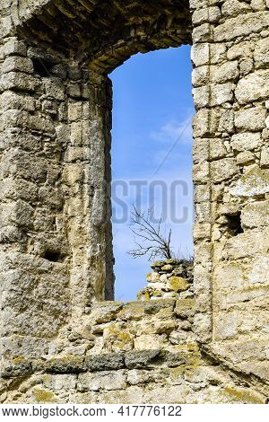 Dilapidated Ancient Synagogue. View Of The Sky Through The Arched Window. The Tree Grows On The Wall