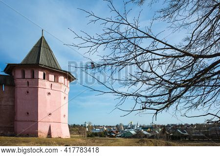 Red observation tower of Saint Euthymius monastery, panorama of Suzdal and tree branches in middle april, Russian heritage architecture. Golden Ring of Russia
