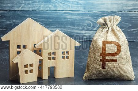 Russian Ruble Money Bag And Figurines Of Residential Buildings. Property Tax. Increase Investment At
