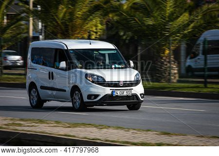 Alanya, Turkey - April 12 2021:   White Fiat Doblo  Is Driving Fast On The Street On A Warm Summer D