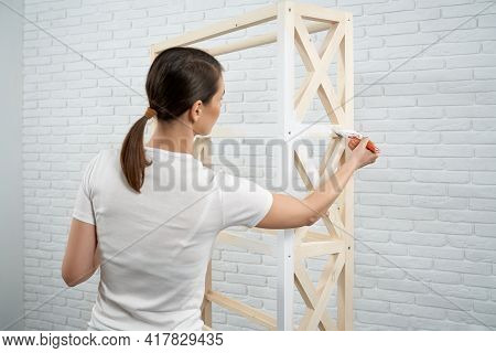Close Up Of Brunette Woman Holding Brush And Painting Small Wooden Rack In White Color. Concept Of R
