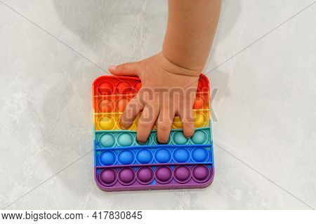 Anonymous Child With Colorful Poppit Game. Close Up Shot Of Kid Hand Playing With Colorful Pop It Fi