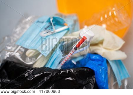 Closeup Of Filed Or Over Flowed Single Use Medical Waste Like Face Masks, Gloves And Syringe On Garb